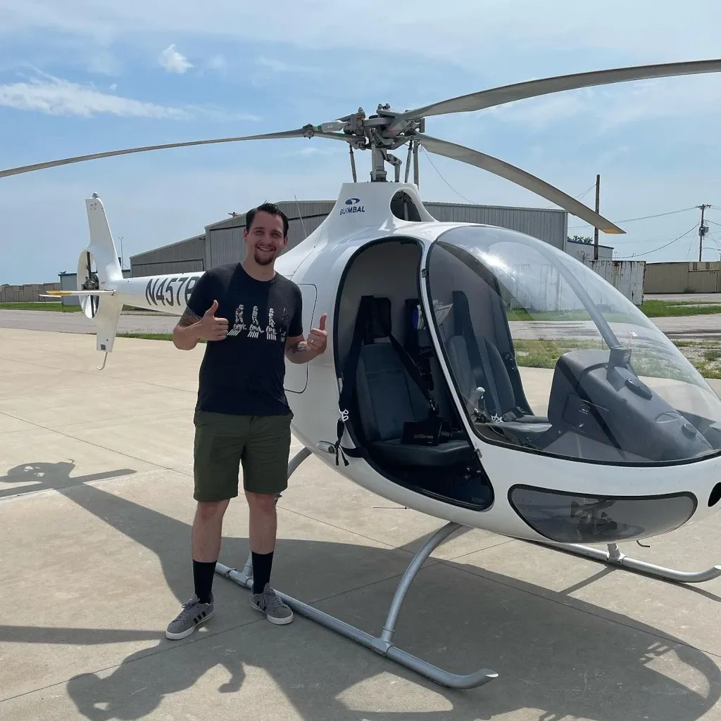 A pilot stands next to a Guimbal Cabri helicopter at Ideal Aviation.