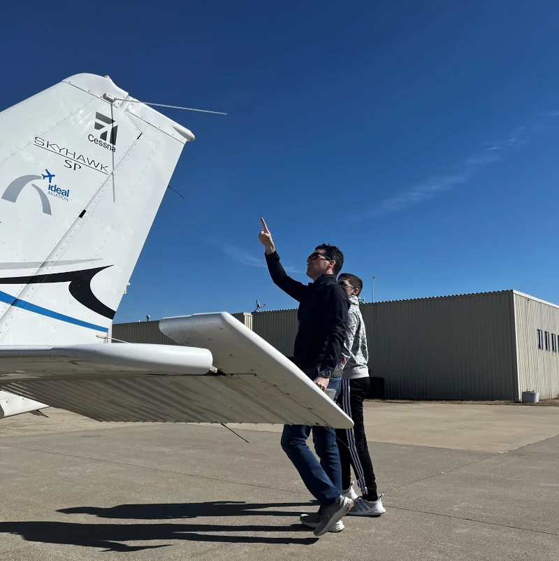 Pilot completing a preflight inspection beside an Ideal Aviation training airplane