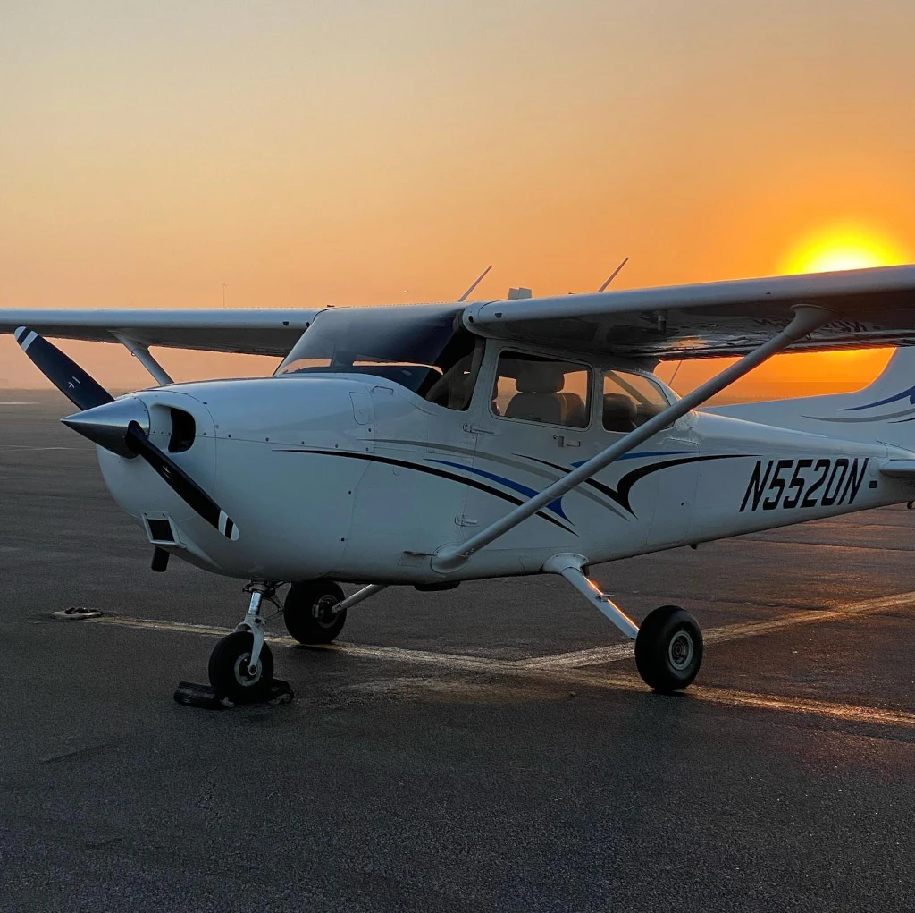 Parked Cessna airplane seen from the front with sunset in the background
