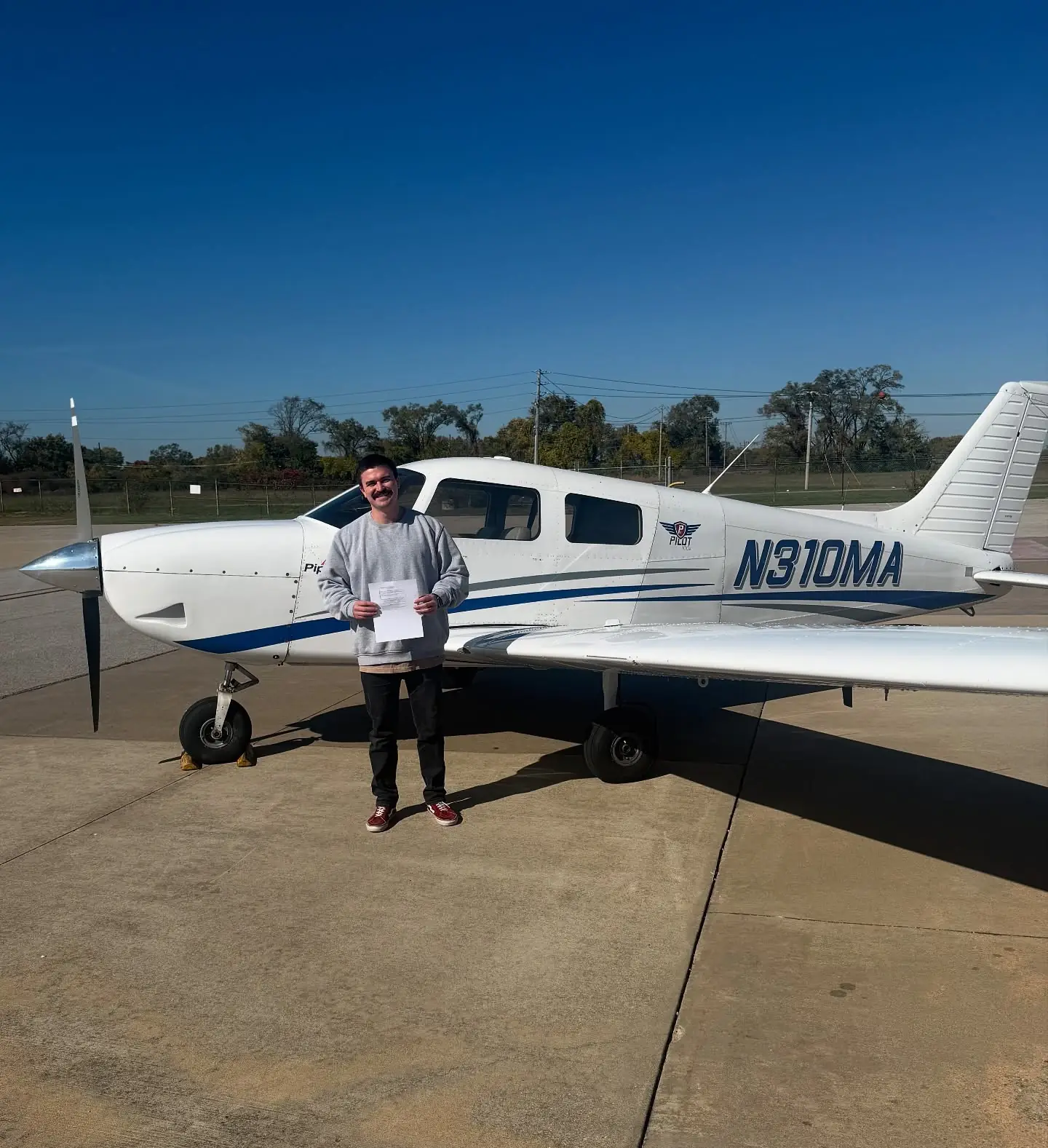 Man holding a certificate beside an airplane