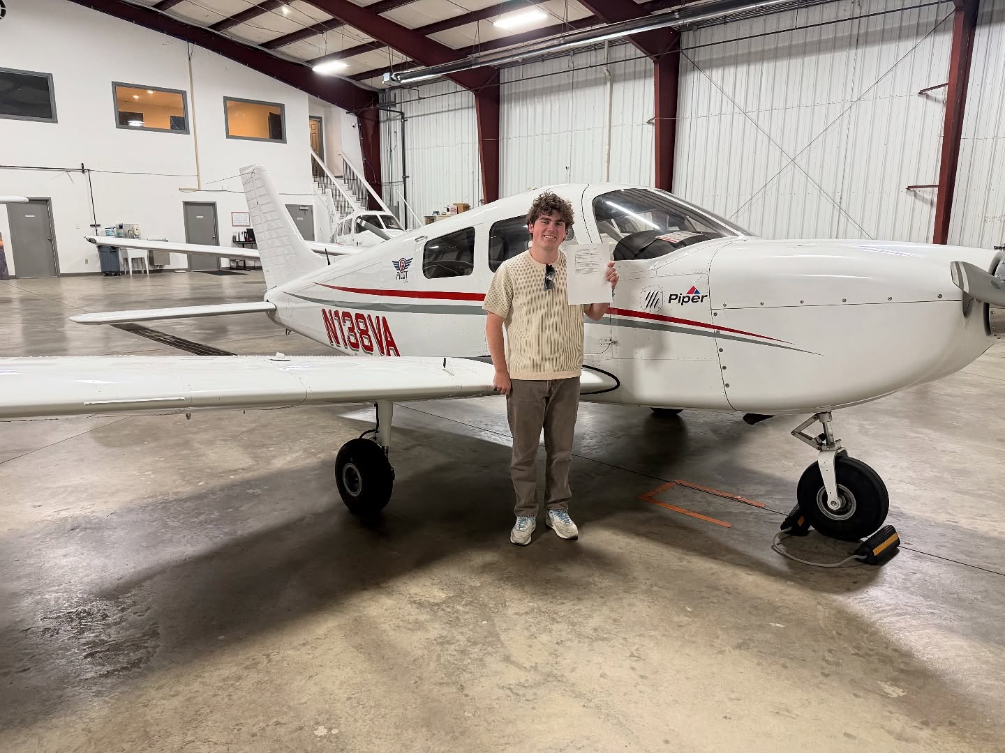 Ideal Aviation student celebrating a pilot certificate beside a Cessna training airplane